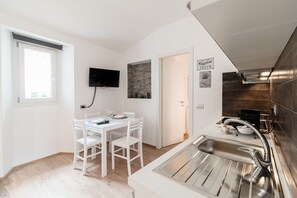 Una cocina compacta con comedor, televisor de pantalla plana y pared decorativa de piedra.