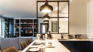 A modern kitchen with a dining area, a coffee maker, and a TV in the background. - Blue Stay - My Home in Como (Riva)