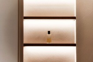 Um frasco de perfume sobre uma prateleira com parede texturizada e moldura marrom.