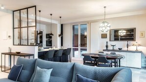 A modern living room with a sofa, dining area, kitchen, and large sliding glass doors. - Blue Stay - My Home in Como (Riva)
