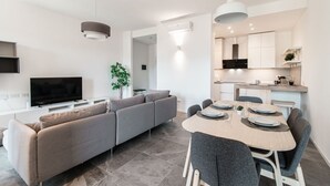 A modern living space with a sofa, TV, dining table, chairs, and a kitchen area. - Friends & Family Retreat - My Home In Como (Como)