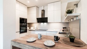 A modern kitchen with white cabinetry, a wooden countertop, and a black range hood. - Friends & Family Retreat - My Home In Como (Como)