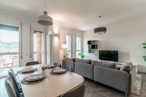 Una sala de estar moderna con comedor, un sofá, un televisor y un balcón con vistas.