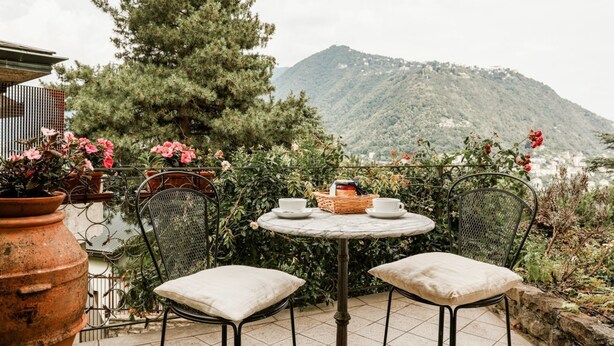 A patio with a round table, two chairs, and a potted plant. - Casa Panoramica - My Home In Como (Como)