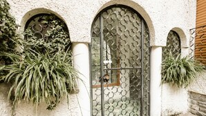 A building with a textured facade, a metal gate with circular patterns, and potted plants. - Casa Panoramica - My Home In Como (Como)