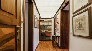 A hallway with wooden flooring, bookshelves, framed artwork, and a door with a geometric pattern. - Casa Panoramica - My Home In Como (Como)