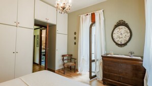 A bedroom with a bed, a dresser, a chair, a chandelier, and a mirror. - Casa Panoramica - My Home In Como (Como)