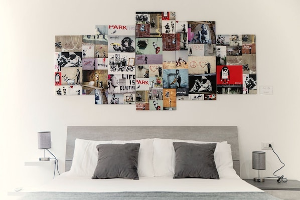 A bedroom with a bed, two bedside tables, and a wall art collage.