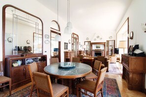 A spacious room with a round table, multiple chairs, and a large mirror.