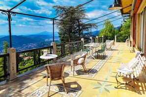 Una terraza con mobiliario de mimbre, una mesa y vistas al paisaje.