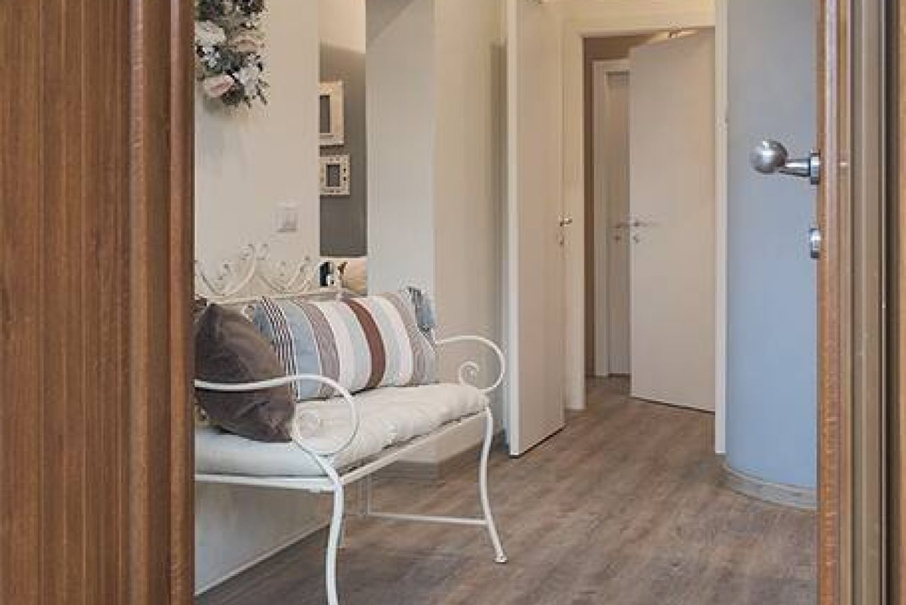 A hallway with a white bench, a door, and a wall-mounted decoration.