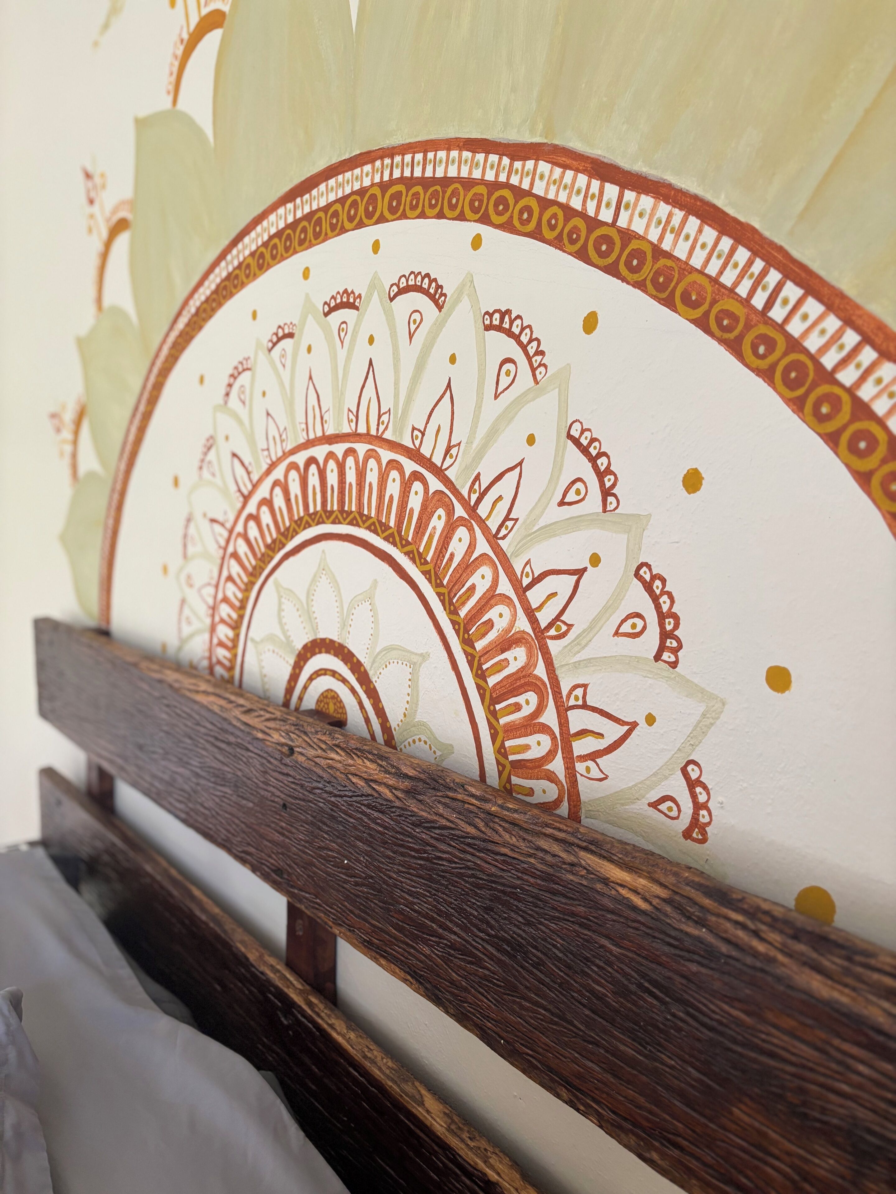 Un mur orné d’un motif décoratif, un banc en bois et un coussin blanc.
