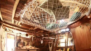 Una habitación rústica de madera con una hamaca, una mesita y una silla.