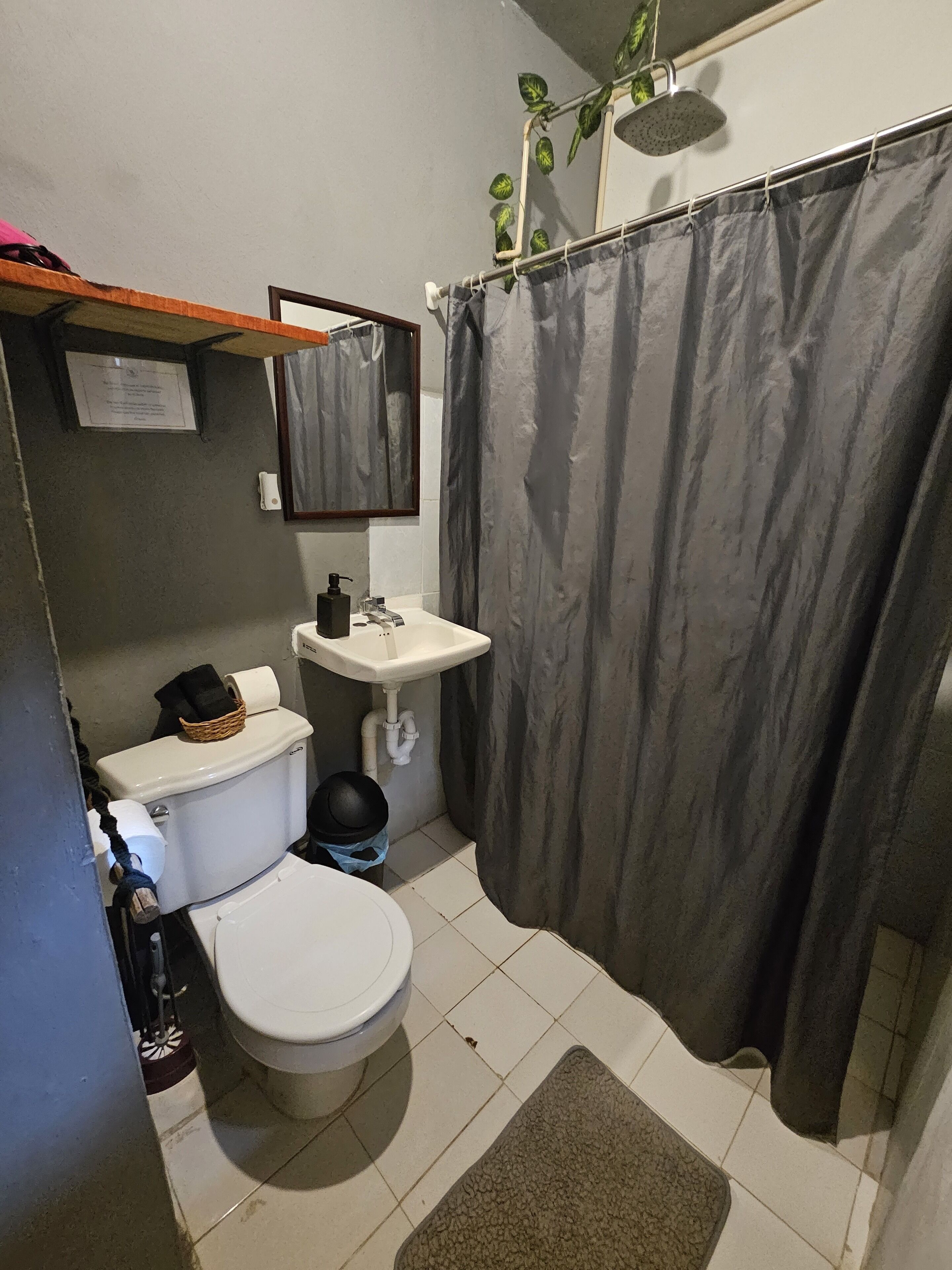 A compact bathroom with a toilet, sink, and shower curtain.