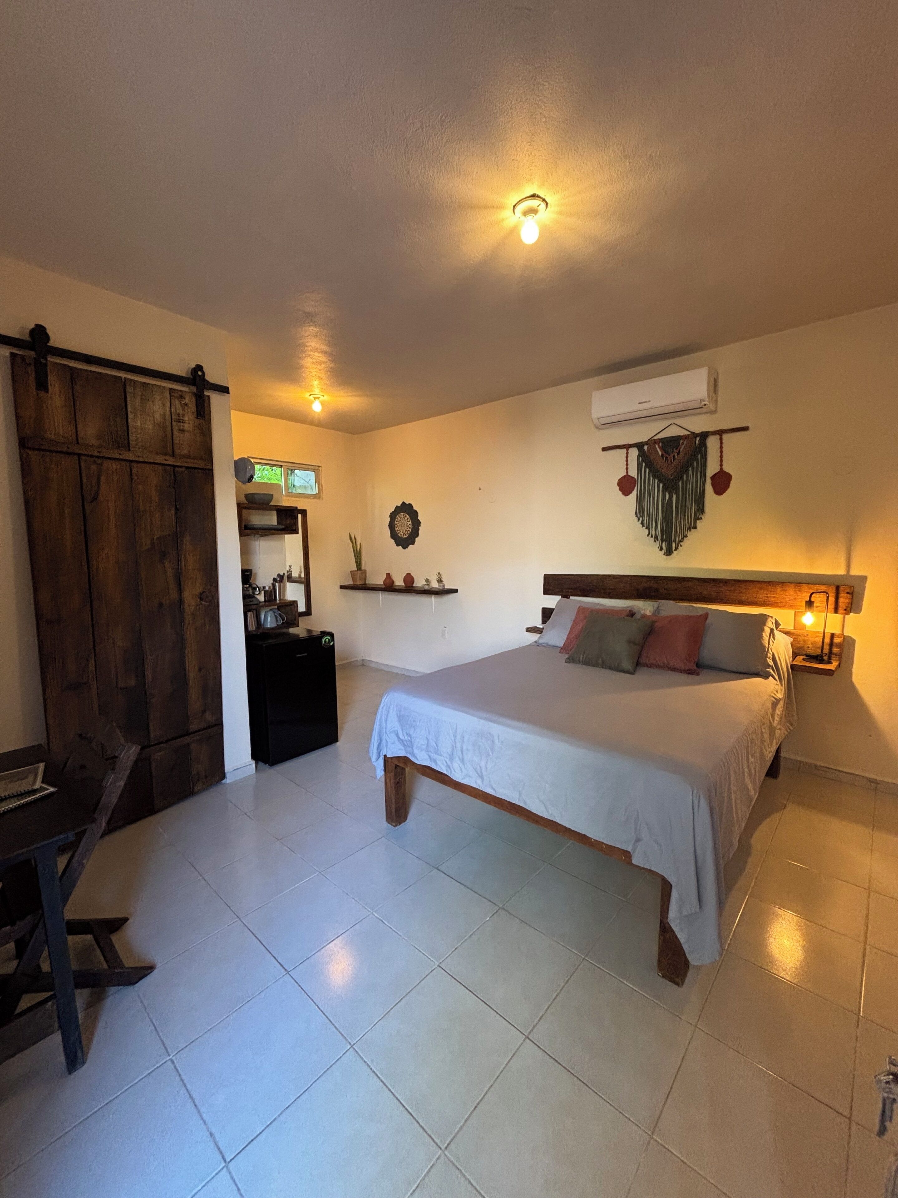 A bedroom with a bed, bedside table, and a desk with a chair.