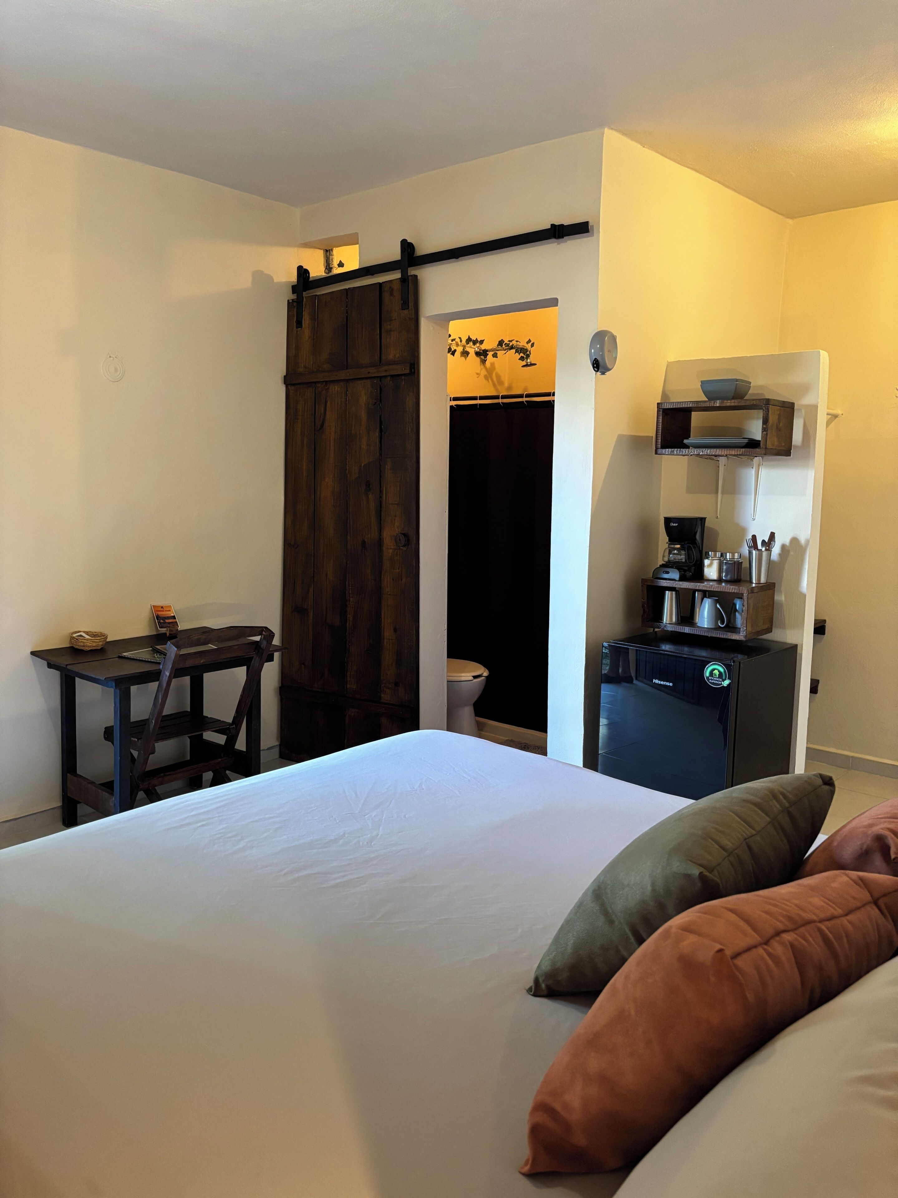 A hotel room with a bed, a desk, a coffee machine, and a sliding door.