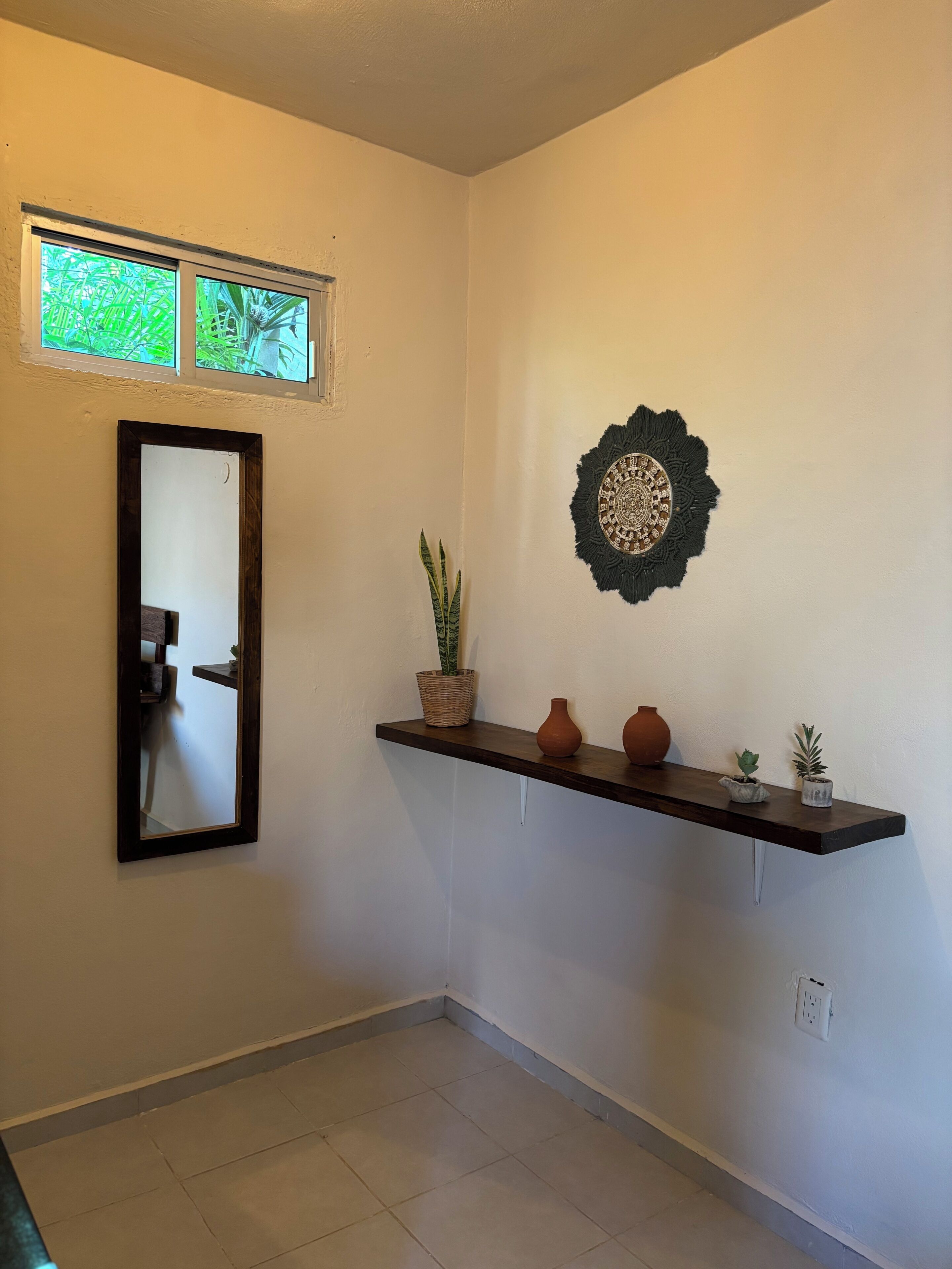 A hallway with a mirror, a decorative wall piece, and a shelf with potted plants.