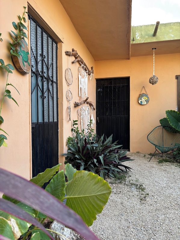 A building exterior with a black gate, decorative wall hangings, and a hanging light fixture. - Jungla Bacalar (Bacalar)