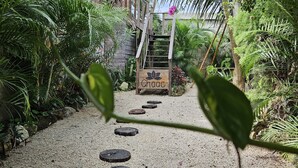 Un sendero en un jardín con un letrero de madera que dice "Chaac" y que lleva a una escalera.