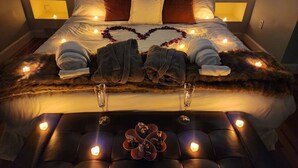 A well-lit bedroom with a bed, pillows, and a heart-shaped decoration made of flowers. - The widow’s walk your very own spa experience (Marblehead)