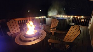 A deck with a fire pit, wooden chairs, and string lights. - The widow’s walk your very own spa experience (Marblehead)