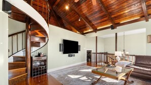 A spacious living area with a wooden staircase, a flat-screen TV, a leather sofa, and a glass coffee table. - The widow’s walk your very own spa experience (Marblehead)