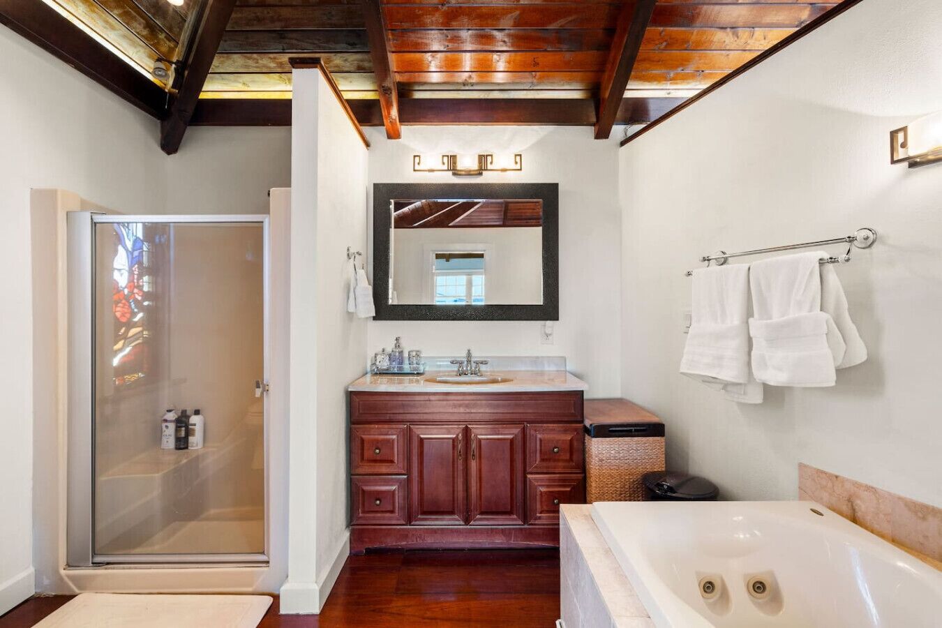 Une salle de bain avec une douche en verre, un meuble-lavabo en bois et un grand miroir.