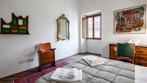 Une pièce comprenant un lit, une chaise, une commode, un miroir et une fenêtre.