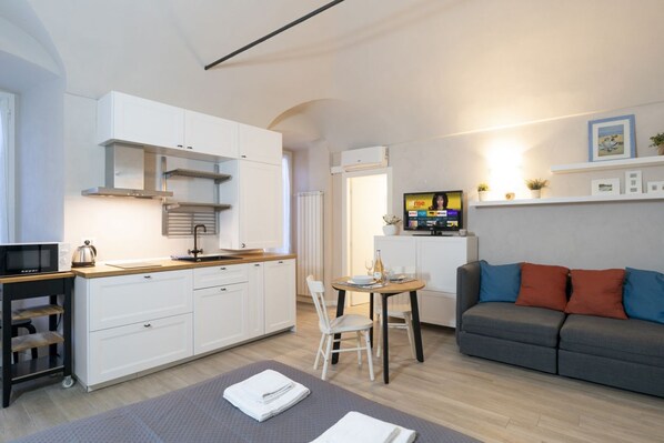 A modern kitchen with white cabinets, a built-in stove, and a dining area with a table and chairs.