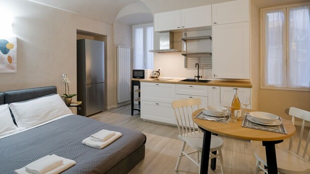 Habitación de hotel compacta con cama, kitchenette, zona de comedor y baño pequeño.