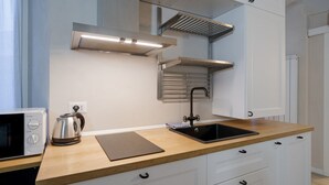 Una cocina moderna con microondas, hervidor y lavabo.
