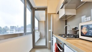 Una cocina moderna con estufa, microondas y vistas de la ciudad a través de un ventanal.