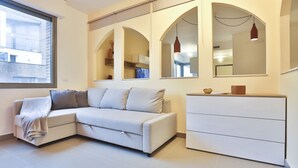 Una sala de estar moderna con un sofá, un aparador blanco y un ventanal grande.