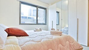 Un dormitorio con cama, almohadas, una ventana y un armario.
