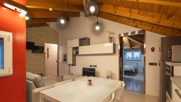 Een moderne keuken met witte kasten, een eettafel en hanglampen.