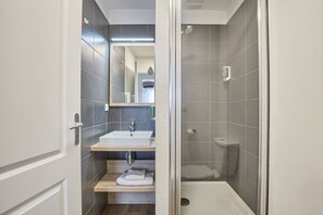 Un baño moderno con ducha, lavamanos y espejo.