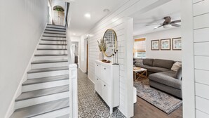 A staircase leading to a living area with a sofa, a coffee table, and a decorative mirror. - Single Family Downtown House with Private Yard (Charleston)