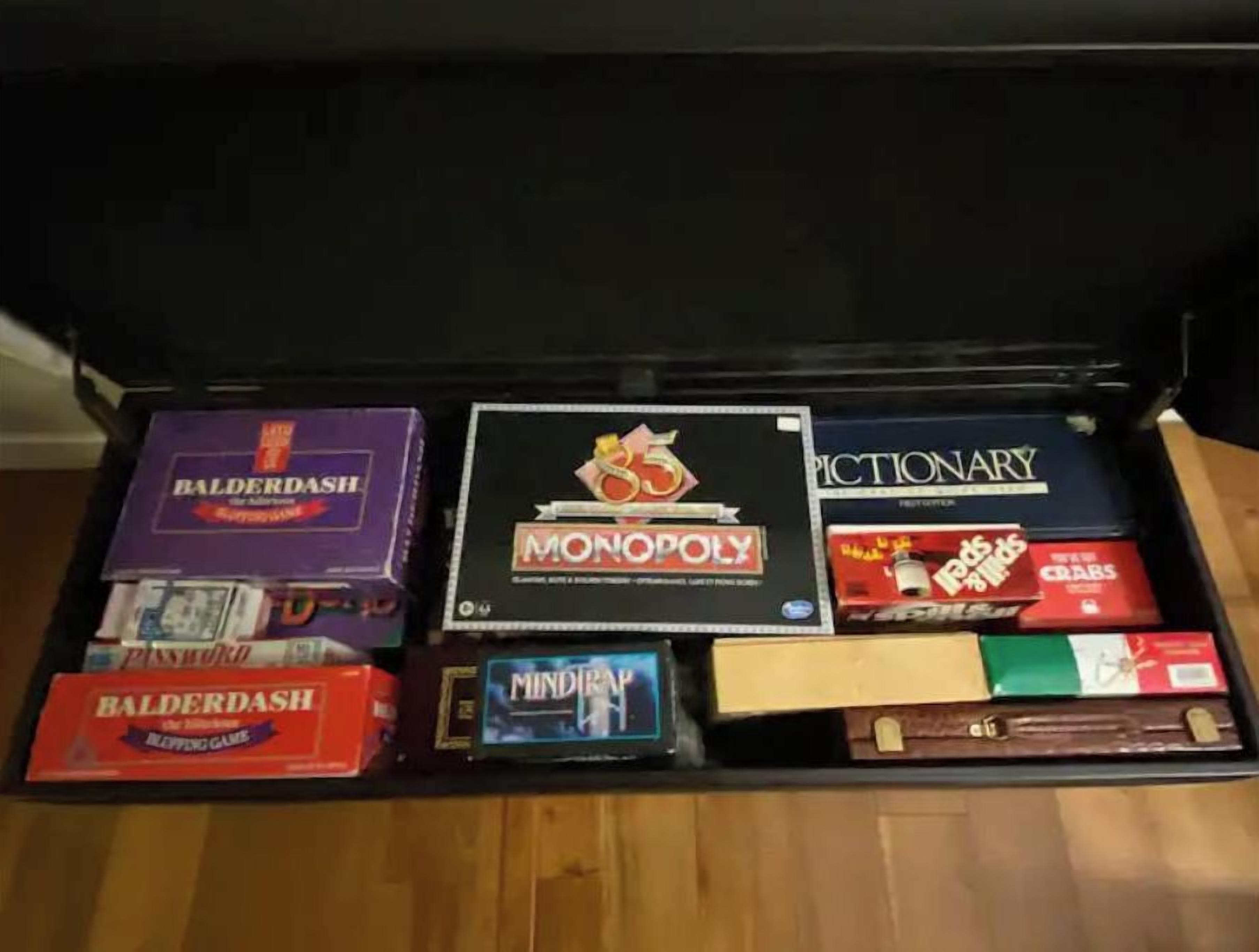 A box of board games including Balderdash, Monopoly, and Scrabble.