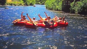 Un grupo de personas haciendo rafting en un río rodeado de vegetación y montañas.