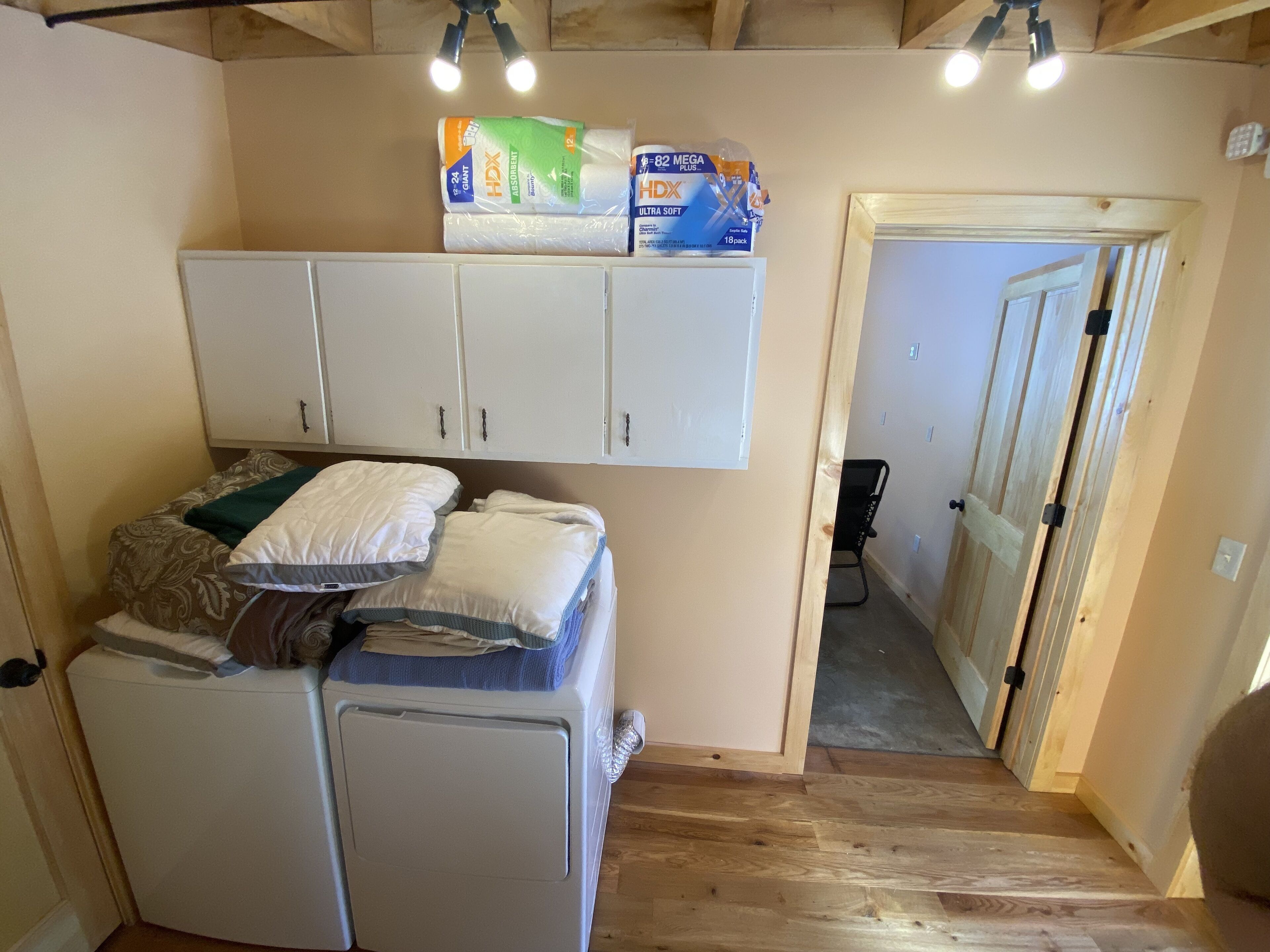 A compact room with a bed, a small white cabinet, and a wooden door leading to another room.