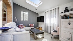 Ein modernes Wohnzimmer mit Oberlichter, einem Flachbildfernseher und einem Bücherregal.