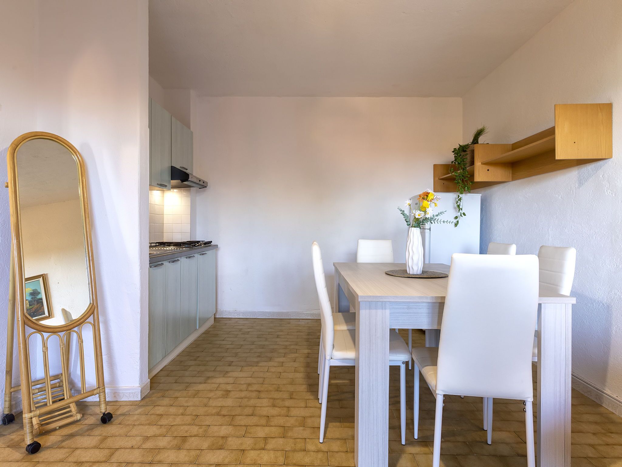 A modern kitchen with white cabinets, a gas stove, and a dining area with white chairs and a table.