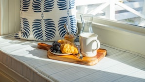 A breakfast setup on a windowsill with a pastry, berries, a cup, and a jar of jam. - Oceanfront Family Retreat + Private Beach Access (Folly Beach)