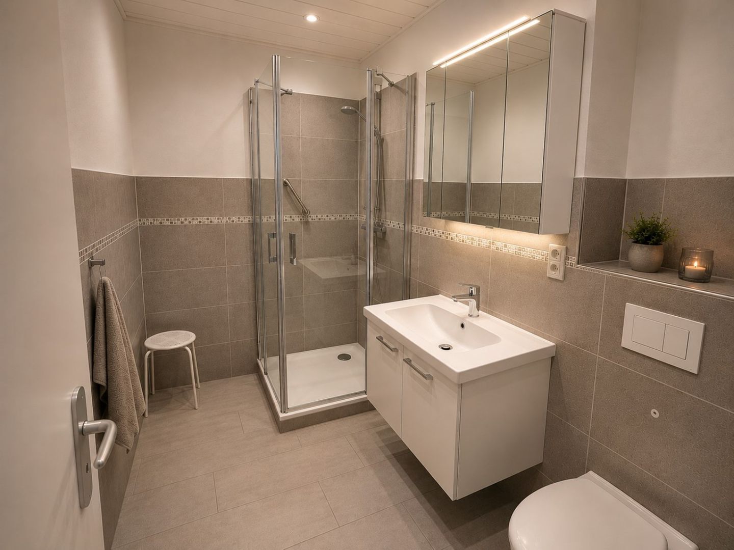 Une salle de bain moderne avec une douche à parois de verre, un lavabo blanc et un grand miroir.