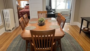 Een eethoek met een houten tafel, stoelen en een plant in het midden.