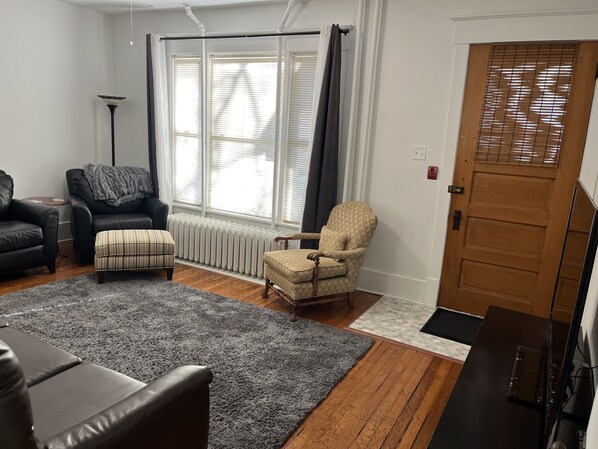 Un salon avec une cheminée, un canapé, un fauteuil et un radiateur.