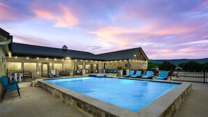 A swimming pool with lounge chairs and a covered area with string lights. - Outdoor kitchen, volleyball, swimming pool & hot tub! (Concan)