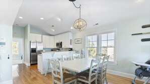 A modern kitchen with white cabinets, stainless steel appliances, and a dining area with a white table and chairs.