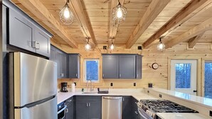 Een moderne keuken met roestvrijstalen apparatuur, houten balken en hanglampen.