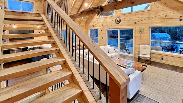 Een houten interieur met een trap, een bank en een eethoek.